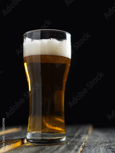 A glass of lager light beer on a dark wooden background