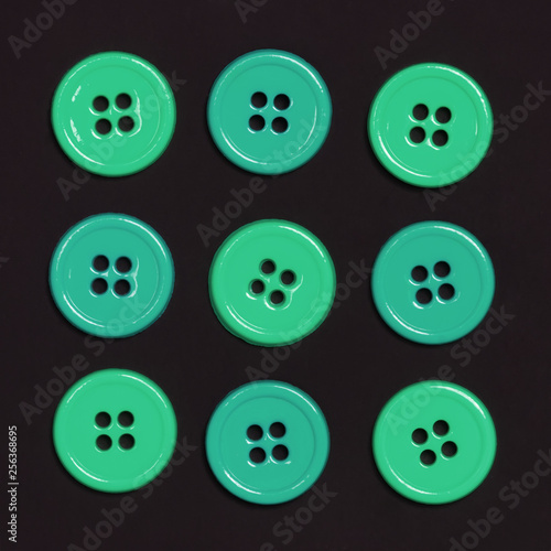 Green sewing buttons in row on a black background