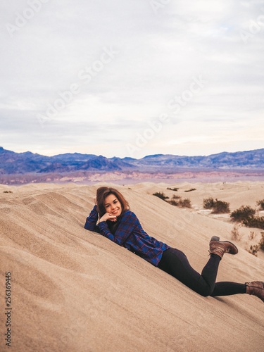 Girl with long hair in a plaid shirt sitting on a sand dune in Death Valley