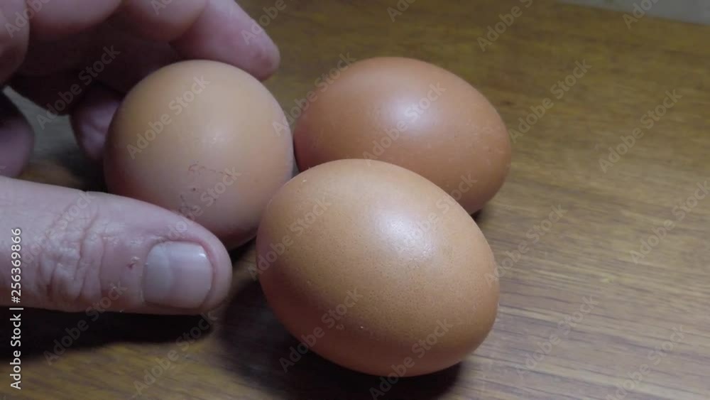 Slow motion hands taking or placing group of brown eggs onto clean wooden natural kitchen surface. Slow motion hands taking or placing group of brown eggs onto clean wooden natural kitchen surface.