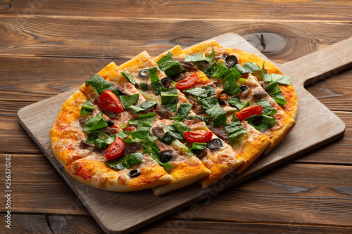 pizza with veal and dried tomatoes on a wooden background