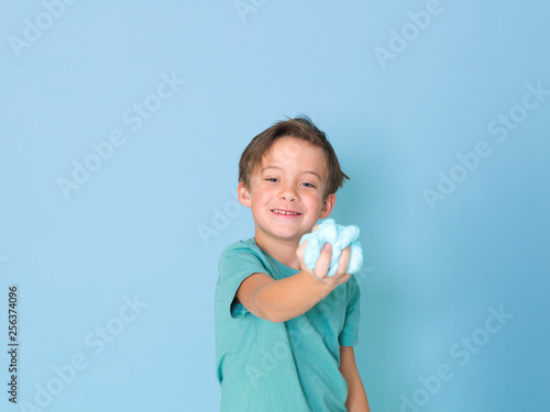 cool, pretty boy plays with homemade slime in front of a blue background and is having a lot of fun