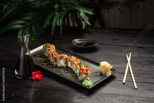 set dragon rolls on a rectangular black plate on a black wooden background