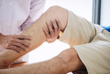 Doctor physiotherapist assisting a male patient while giving exercising treatment massaging the leg of patient in a physio room, rehabilitation physiotherapy concept