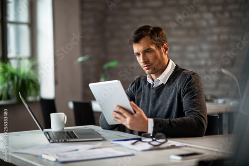 Male entrepreneur using digital tablet while working in the office.