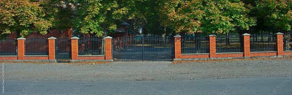 Simple metal fence with red bricks wall and pillars Simple metal fence with red bricks wall and pillars