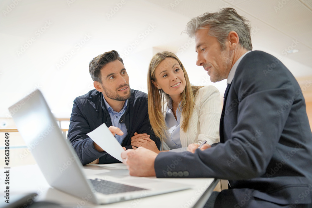 Fototapeta premium Couple signing contract with real estate agent