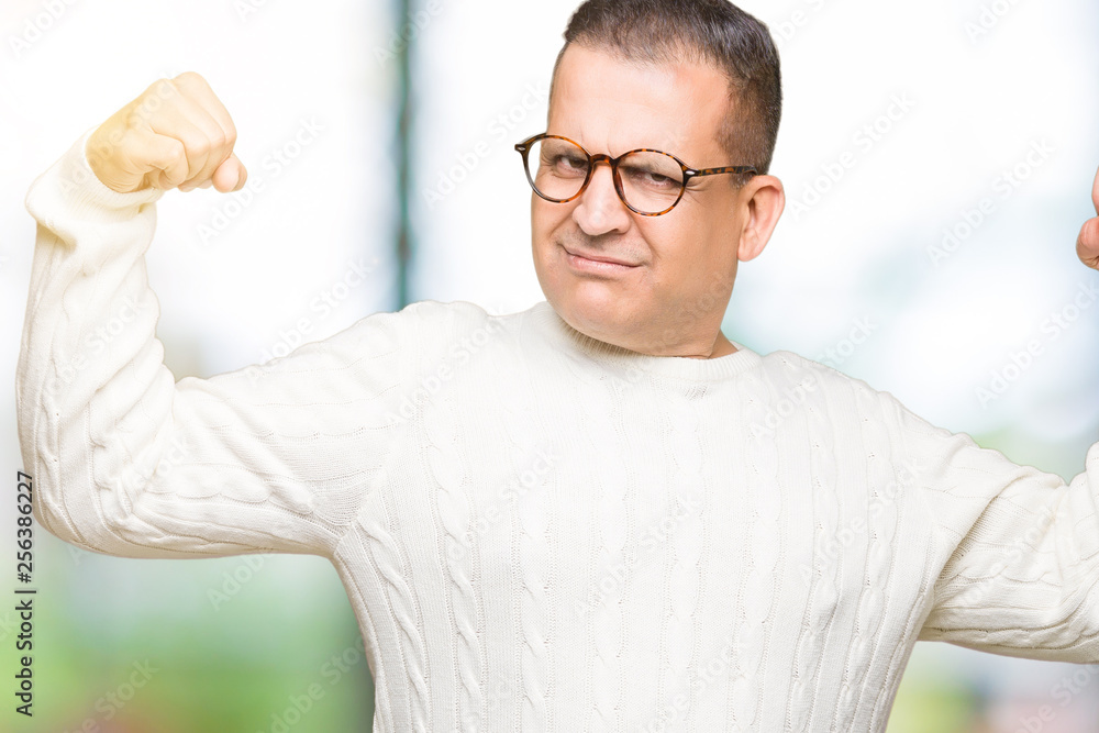 Middle age arab man wearing glasses over isolated background showing arms muscles smiling proud. Fitness concept. Middle age arab man wearing glasses over isolated background showing arms muscles smiling proud. Fitness concept.