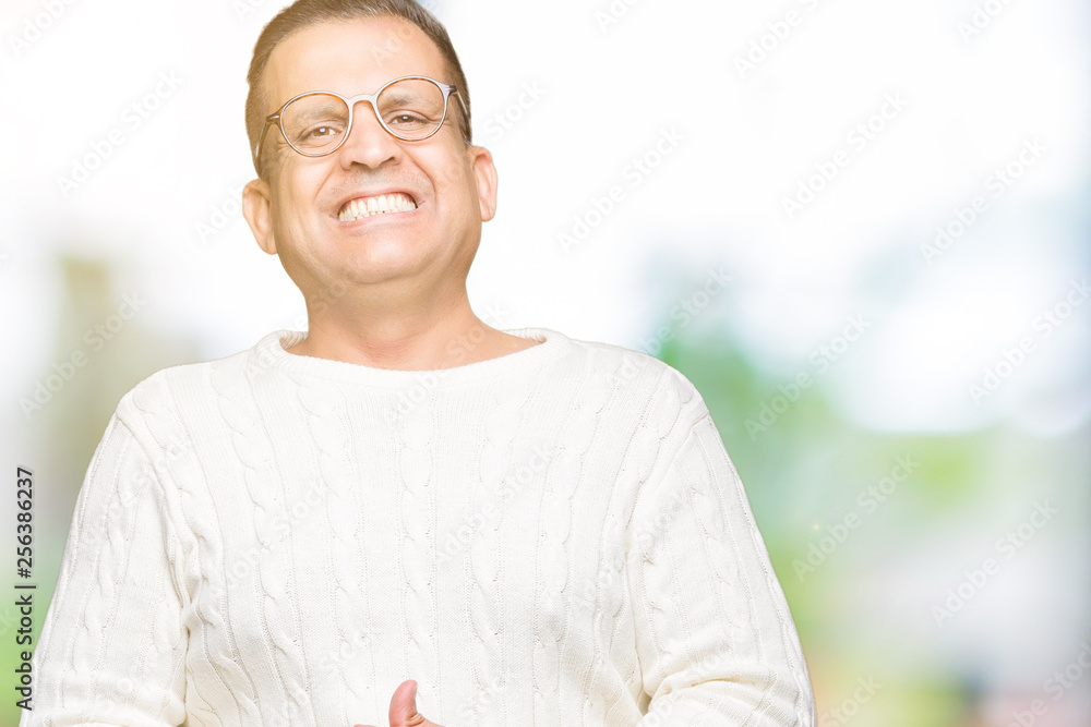 Obraz premium Middle age arab man wearing glasses over isolated background Hands together and fingers crossed smiling relaxed and cheerful. Success and optimistic