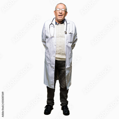 Handsome senior doctor man wearing medical coat winking looking at the camera with sexy expression, cheerful and happy face. © Krakenimages.com