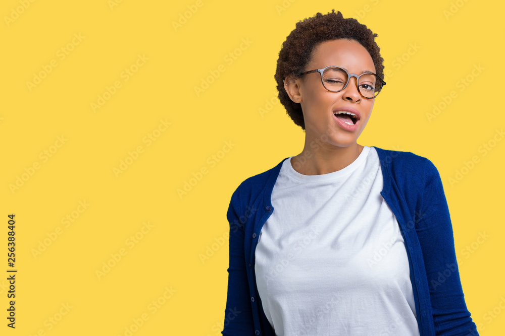 Young beautiful african american woman wearing glasses over isolated background winking looking at the camera with sexy expression, cheerful and happy face. Young beautiful african american woman wearing glasses over isolated background winking looking at the camera with sexy expression, cheerful and happy face.
