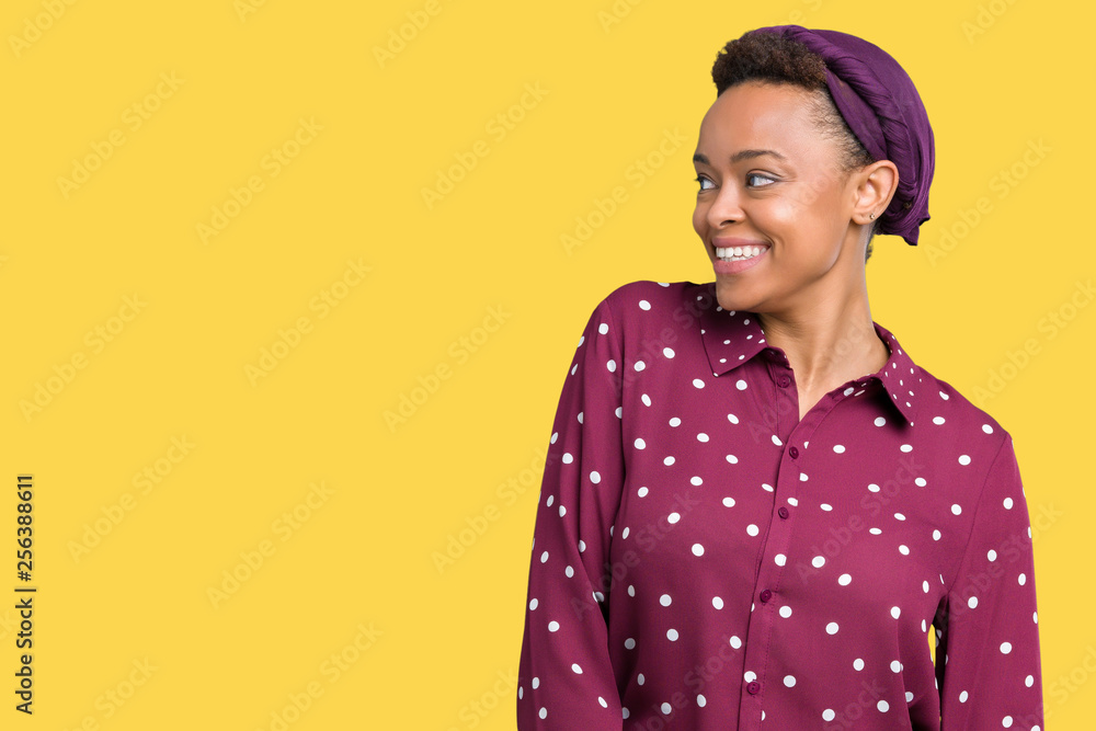 Beautiful young african american woman wearing head scarf over isolated background looking away to side with smile on face, natural expression. Laughing confident. Beautiful young african american woman wearing head scarf over isolated background looking away to side with smile on face, natural expression. Laughing confident.
