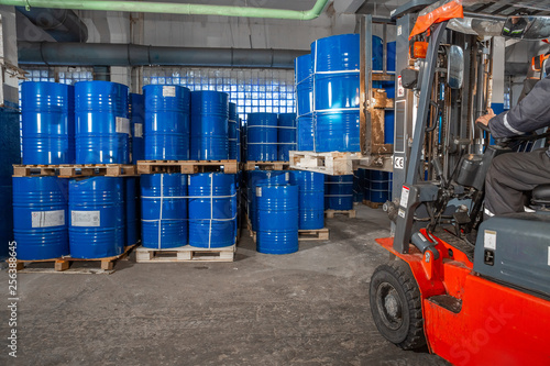 Photography blue barrels and red forklift in warehouse