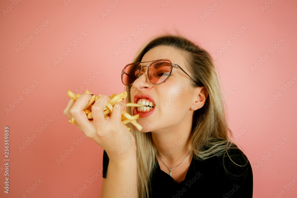 the girl eats French fries on a pink background, the girl originally blows out the French fries like a match, a beautiful young girl eats fast food the girl eats French fries on a pink background, the girl originally blows out the French fries like a match, a beautiful young girl eats fast food