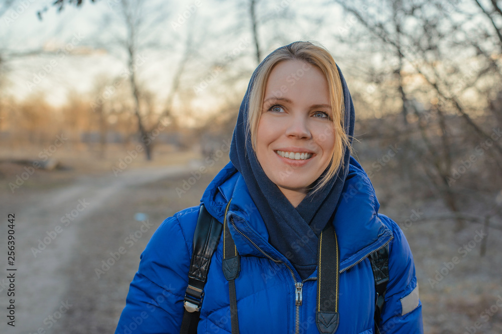 A middle-aged woman in a warm jacket is smiling on nature. A middle-aged woman in a warm jacket is smiling on nature.