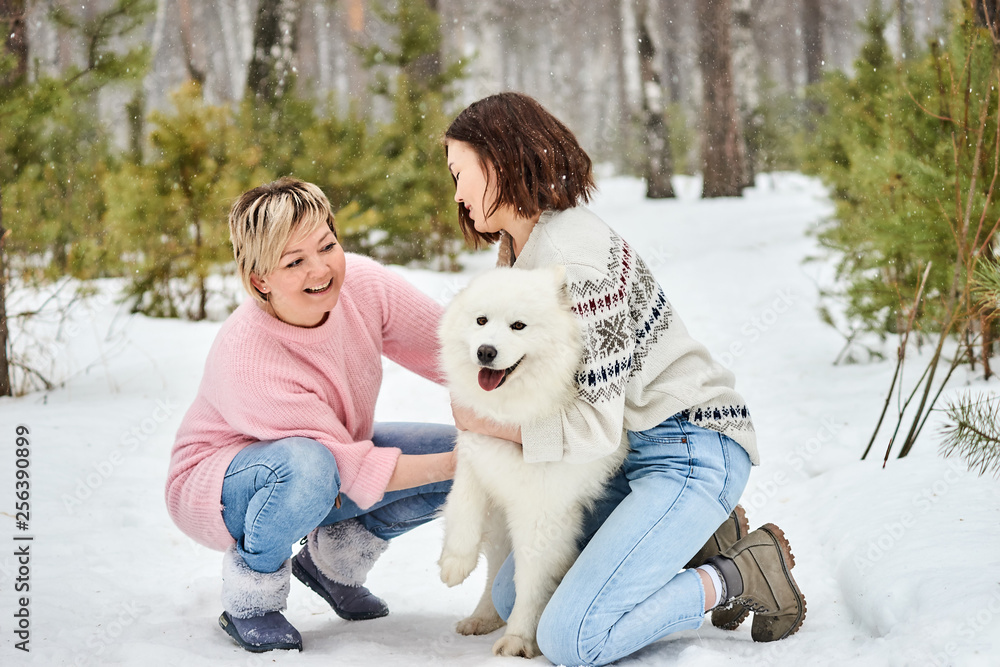 Mother and daughter play with dog in winter the forest Mother and daughter play with dog in winter the forest