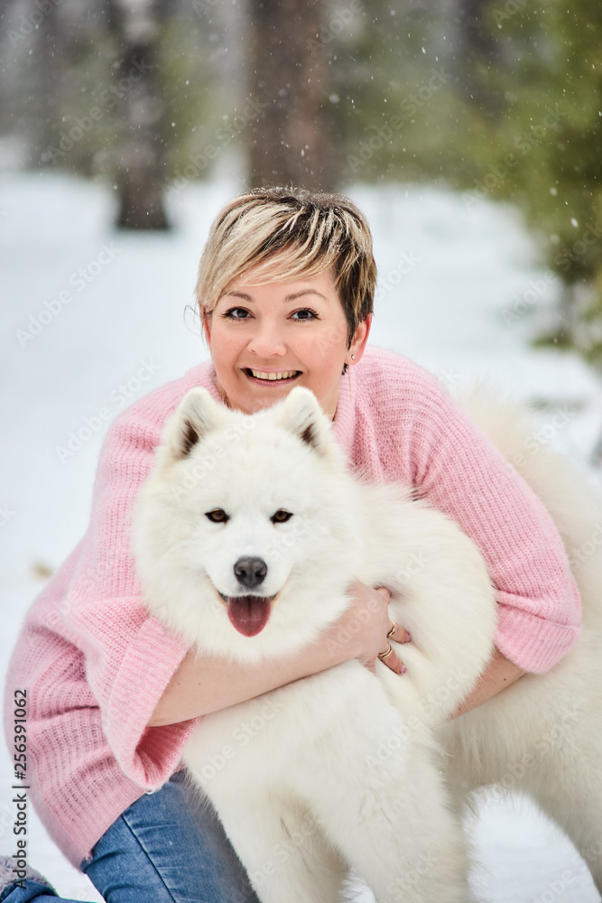 Woman in the winter forest walking with a dog. Snow is falling Woman in the winter forest walking with a dog. Snow is falling