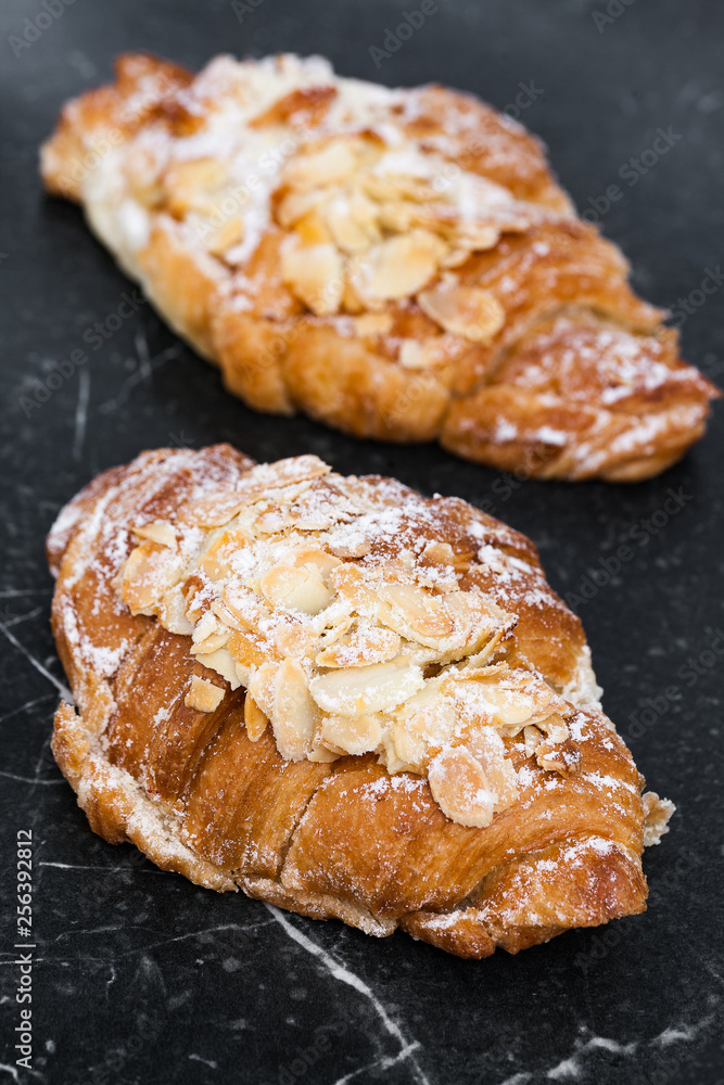 Two fresh croissant with almond cream on marble black background. Close up