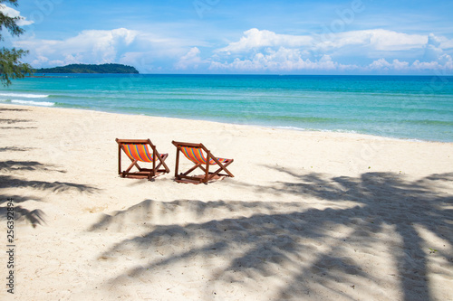 Tropical beach perfect place for relaxing  Empty chairs and shadow palm tree on the beach near the sea.