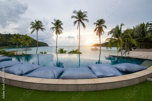 Infinity swimming pool modern luxury hotel, The hotel luxury swimming pool overlooks a wooden bridge that stretches out to the sea at Koh Kood in Thailand.