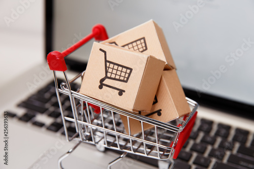 paper boxes in a shopping cart on a laptop keyboard. Concepts about online shopping that consumers can buy things directly from their home or office just using a few clicks via web browser.