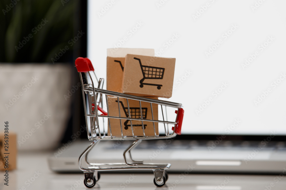 paper boxes in a shopping cart on a laptop keyboard. Concepts about online shopping that consumers can buy things directly from their home or office just using a few clicks via web browser.