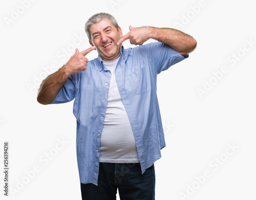 Handsome senior man over isolated background smiling confident showing and pointing with fingers teeth and mouth. Health concept.