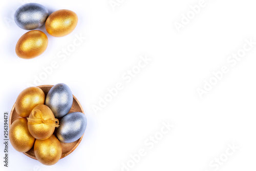 Golden and silver colored Easter eggs in wooden plate isolated on white background. Place for text.