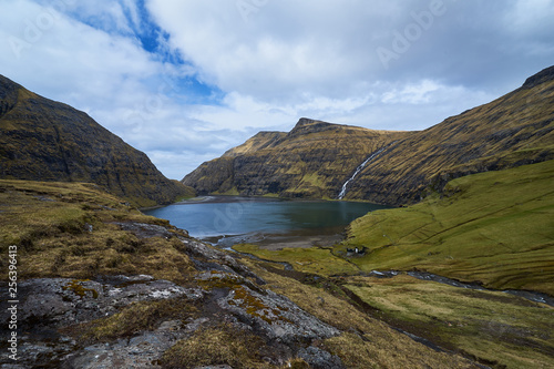 Scenic landscape picture on sea water lagoon or lake between mountains without trees in willage Saksun or danish Saksen in faroese island Streymoy in north atlantic in spring sunny  cloudy morning. 