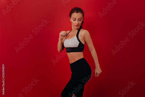 Fototapeta Naklejka Na Ścianę i Meble -   Athletic Woman in sportswear running over red isolated background. portrait of healthy young caucasian woman sprinting