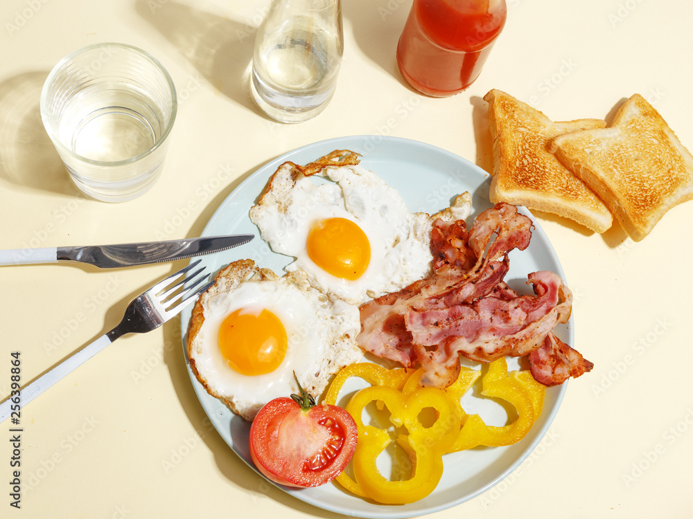 Simple breakfast. Fried egg with bacon, bell pepper and toast on a plate. Simple breakfast. Fried egg with bacon, bell pepper and toast on a plate.