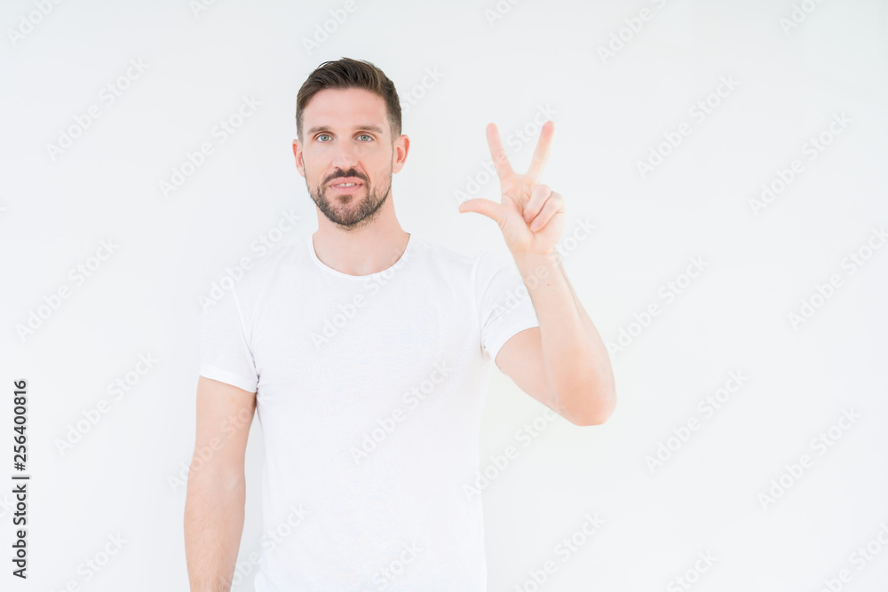 Young handsome man wearing casual white t-shirt over isolated background showing and pointing up with fingers number three while smiling confident and happy. Young handsome man wearing casual white t-shirt over isolated background showing and pointing up with fingers number three while smiling confident and happy.