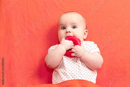Foto Infant chews teething ring against living coral trendy color background