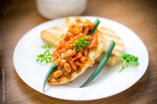 fried bread toasts with stewed beans and vegetables in a plate