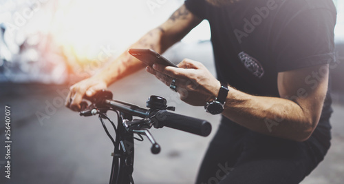 Tattooed hipster man in holding smartphone hands and using maps app before riding by electric scooter in the city. Innovative transport