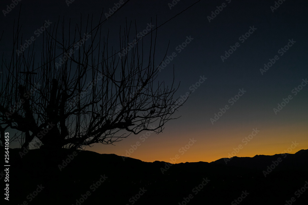 The orange glow of a sunset behind a distant mountain range