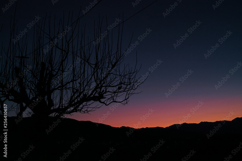 The red glow of a sunset behind a distant mountain range