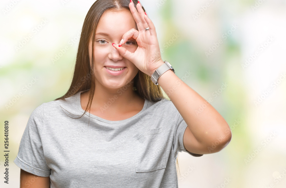 Young caucasian beautiful woman over isolated background doing ok gesture with hand smiling, eye looking through fingers with happy face.