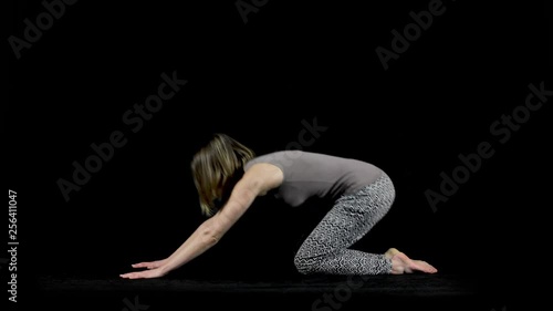 Full body side view of a woman demonstrating various yoga poses including the cat and cow pose isolated on a black studio background photo