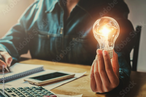 business woman hand holding light bulb in office. conept saving energy photo