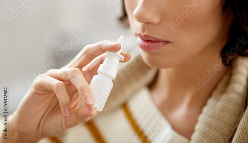 rhinitis, medicine and healthcare concept - close up of sick woman using nasal spray photo