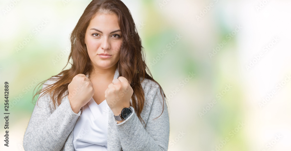 Beautiful plus size young woman wearing winter jacket over isolated background Ready to fight with fist defense gesture, angry and upset face, afraid of problem