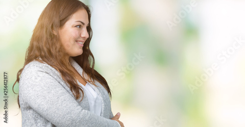 Beautiful plus size young woman wearing winter jacket over isolated background smiling looking to the side with arms crossed convinced and confident