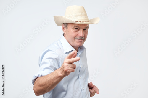 mature man wearing cowboy in studio. He is looking at camera with confidence