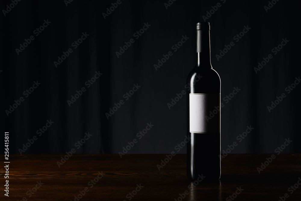Wine bottle with blank label on wooden surface on dark