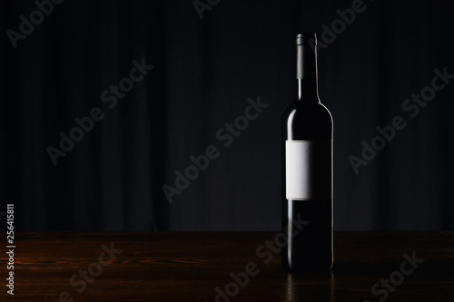 Wine bottle with blank label on wooden surface on dark