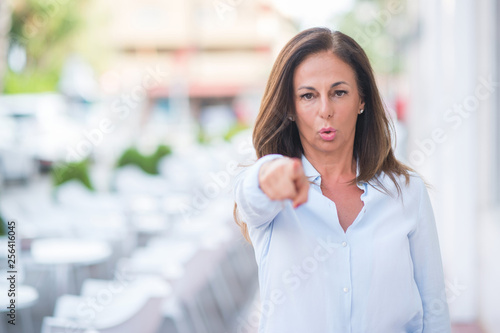 Beautiful middle age hispanic woman at the city street on a sunny day pointing with finger to the camera and to you, hand sign, positive and confident gesture from the front