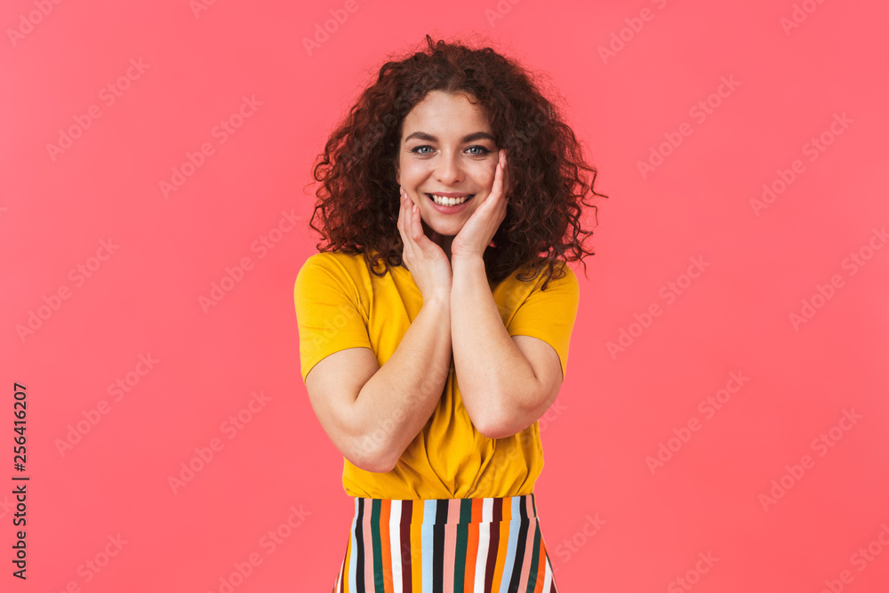 Cute happy beautiful young curly girl posing isolated over red wall background. Cute happy beautiful young curly girl posing isolated over red wall background.