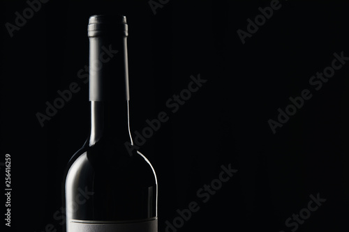 Bottle of wine with dark wrapper isolated on black