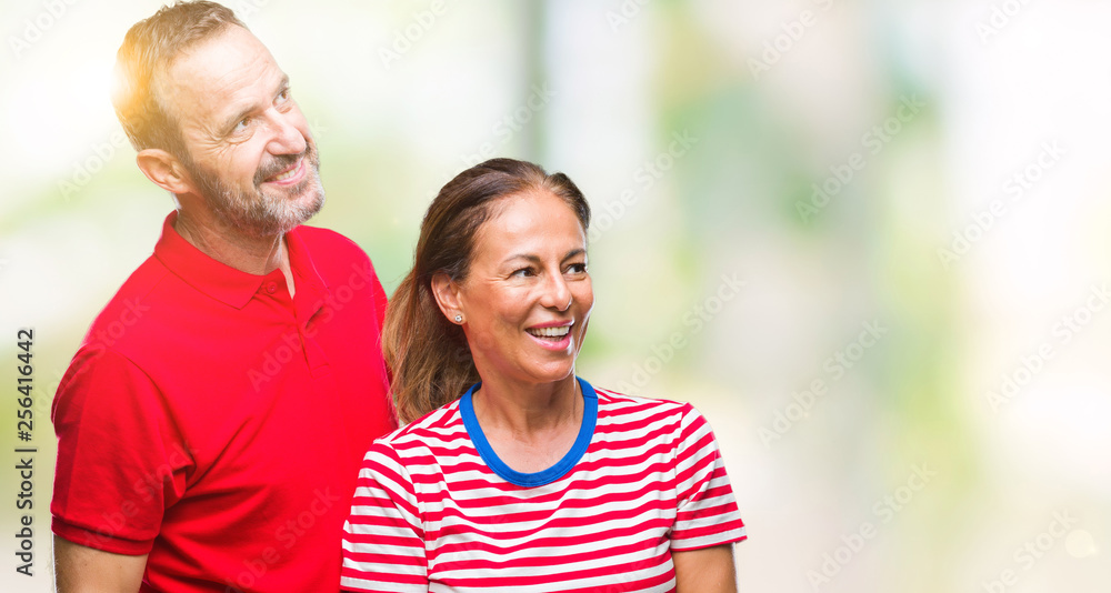 Middle age hispanic couple in love over isolated background looking away to side with smile on face, natural expression. Laughing confident. Middle age hispanic couple in love over isolated background looking away to side with smile on face, natural expression. Laughing confident.